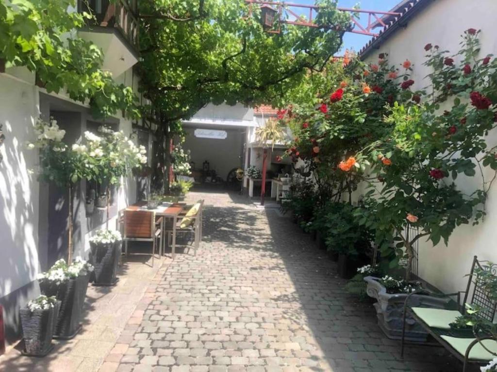 eine Gasse mit Blumen, Tischen und Stühlen in der Unterkunft Ferienwohnung im 'Schmoller - Hof' in Neustadt an der Weinstraße