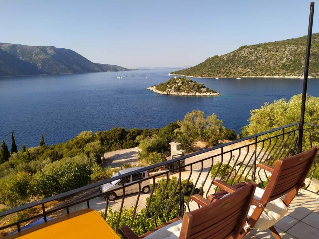 a balcony with two chairs and a view of a lake at Olympia House in Vathi