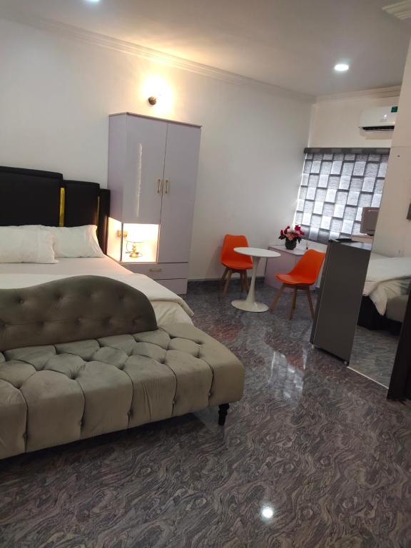 um quarto com uma cama, uma mesa e cadeiras em Kemzie's Apartments em Port Harcourt