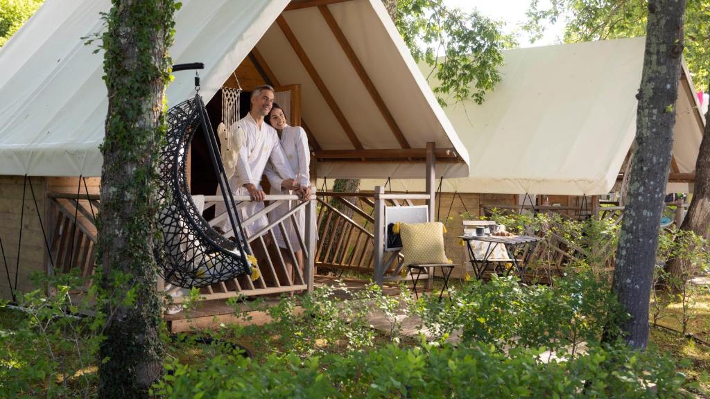 a group of three people standing on the porch of a house at Polidor Glamping Resort in Poreč