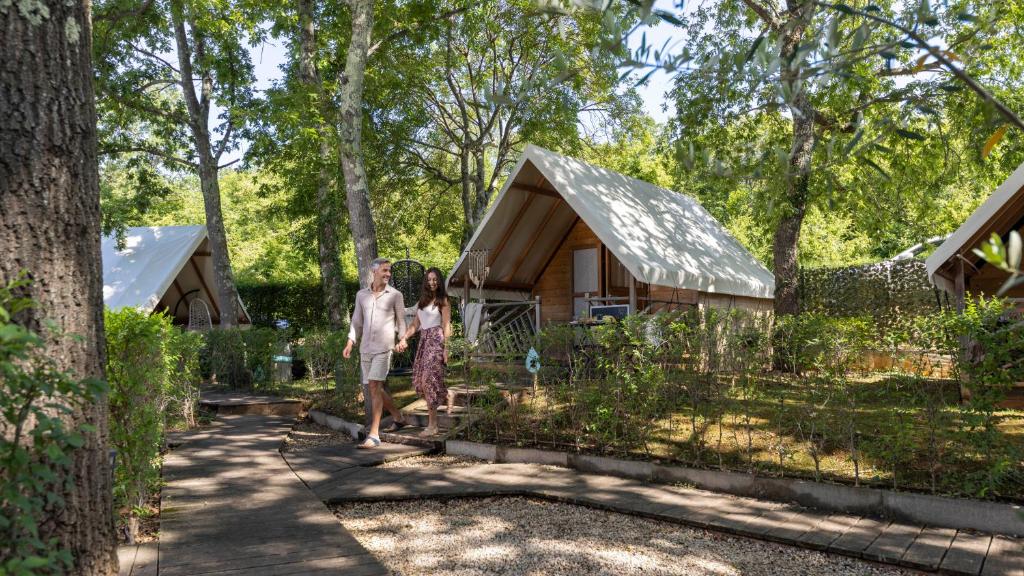 a man and a woman walking in front of a cabin at Polidor Glamping Resort in Poreč