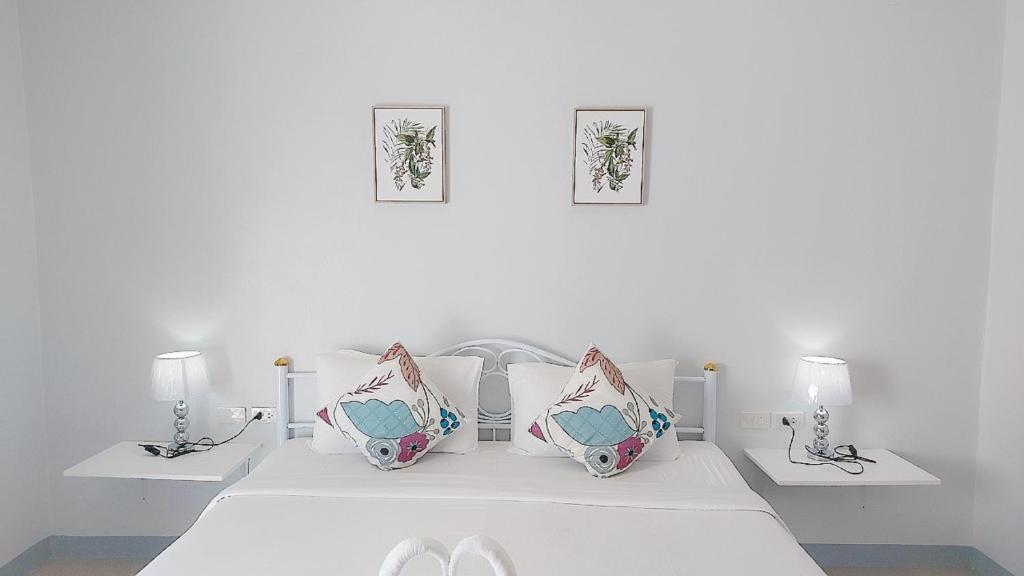 a white bedroom with two lamps and a bed at Cinderella Residence in Patong Beach