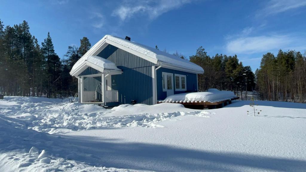 un bâtiment bleu avec de la neige à l'avant dans l'établissement SINITALO, à Inari