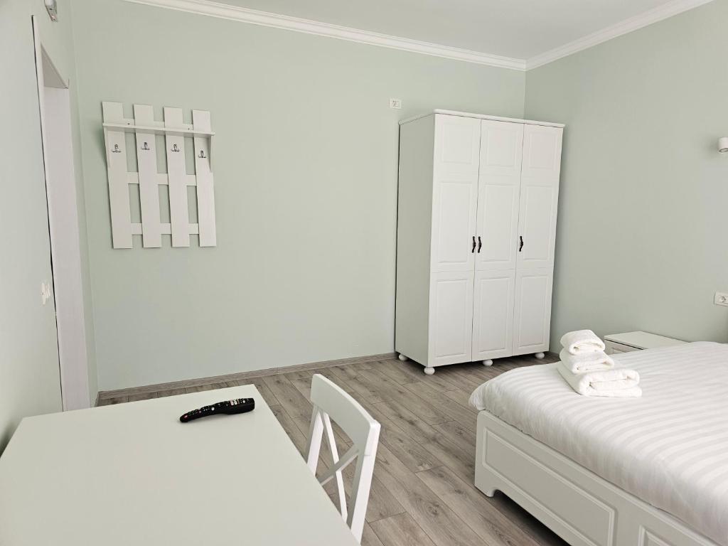 a white bedroom with two beds and a cabinet at Colț de Rai in Hîrtoape