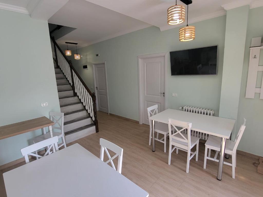 a dining room with white tables and chairs and a staircase at Colț de Rai in Hîrtoape