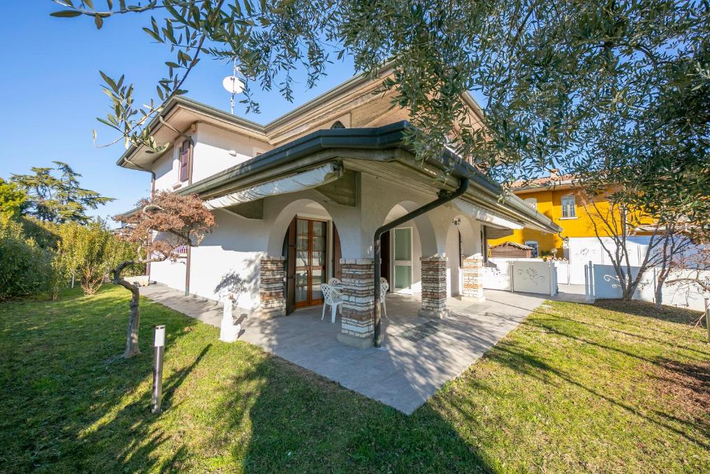 een huis met een veranda en een gazon bij Villa Fiorita Apartments - Happy Rentals in Sirmione