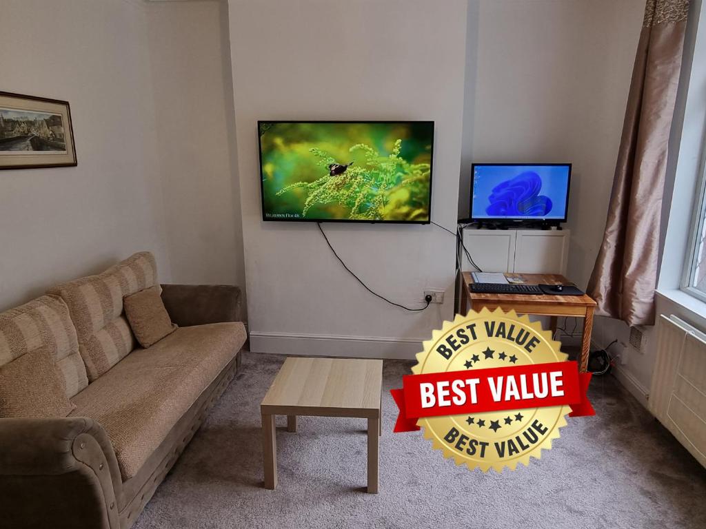 a living room with a couch and a tv on the wall at 3 Bedroom House Free Parking & Fast Wi-Fi Spacious near Rochdale Centre in Rochdale