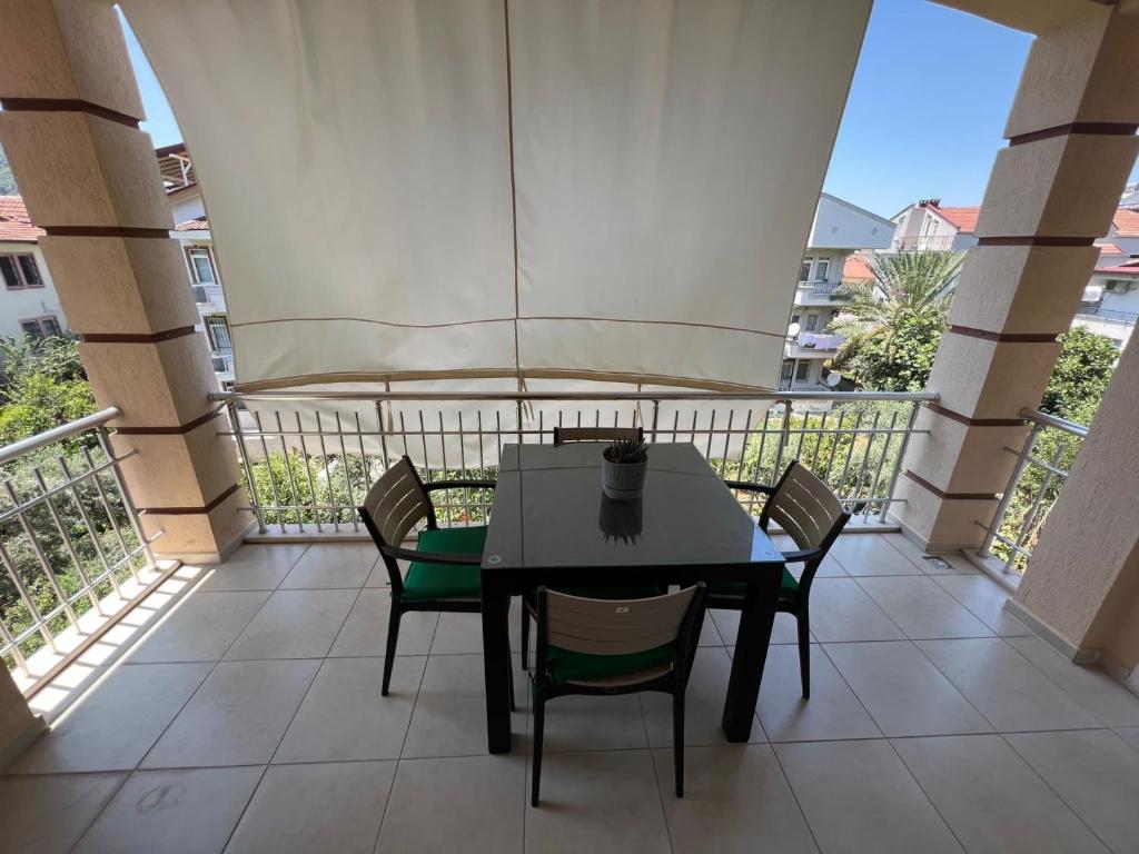 einen Tisch und Stühle auf einem Balkon mit Sonnenschirm in der Unterkunft Tanaydın Evleri in Fethiye