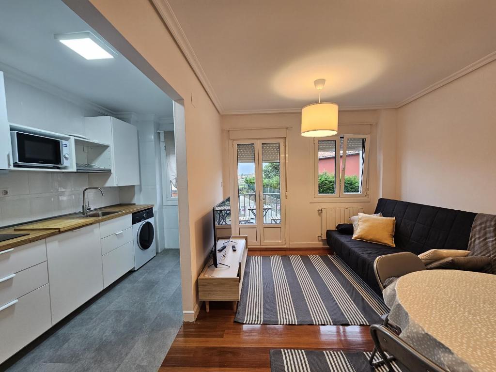 een woonkamer met een zwarte bank en een keuken bij C12A01 Coqueto apartamento con piscina y garaje in Suances