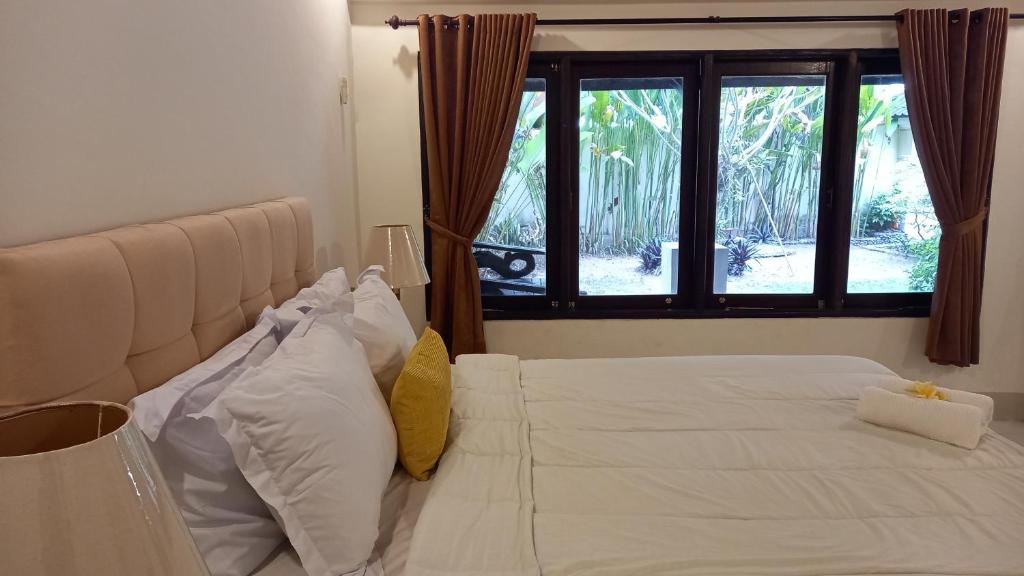 a bedroom with a white bed with pillows and a window at Rumah Jepun in Mataram