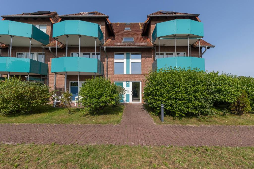 a brick building with blue balconies and a walkway at ST33-22 - Appartement Typ D in Dorum Neufeld