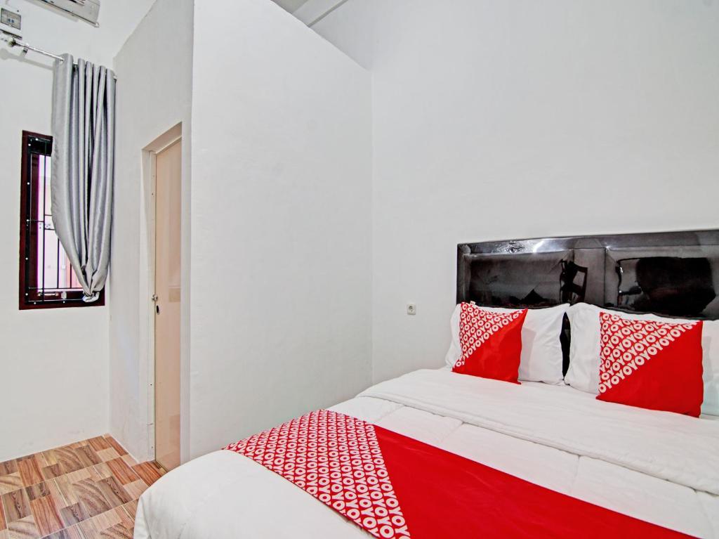 - un lit rouge et blanc avec des oreillers rouges et blancs dans l'établissement OYO 92946 Dekna Homestay Syariah, à Pekanbaru