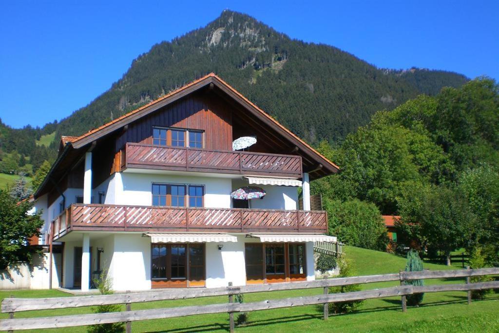 ein Haus mit einem Zaun vor einem Berg in der Unterkunft Ferienwohnung Stoll Helga in Burgberg