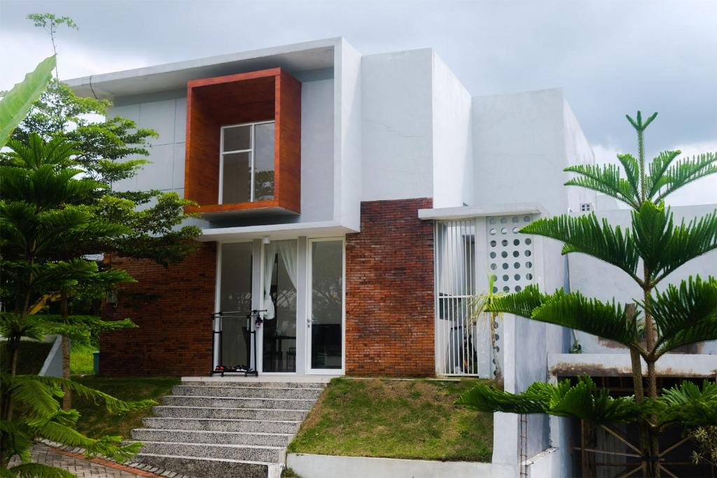 a white house with a red window and stairs at Privat Homestay Malang Oz HK 39 in Dau