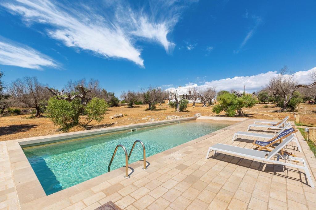 - une piscine avec des chaises longues à côté d'un champ dans l'établissement Tenuta Terra del Sole by Perle di Puglia, à Ugento