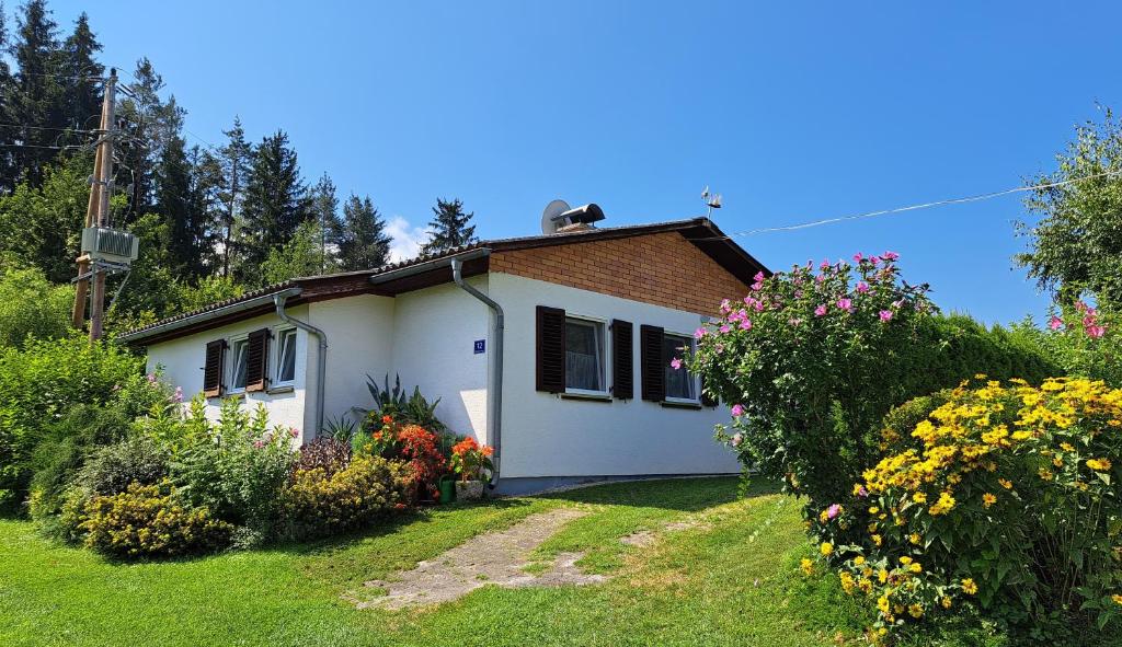 ein kleines weißes Haus mit Blumen im Hof in der Unterkunft Bungalow Raschun Grabelsdorf Etruskerweg 12 / 9122 St. Kanzian in Grabelsdorf