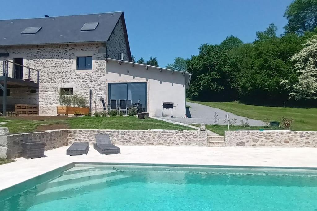 una casa de piedra con piscina frente a ella en Appartement au sud de la Creuse avec piscine 