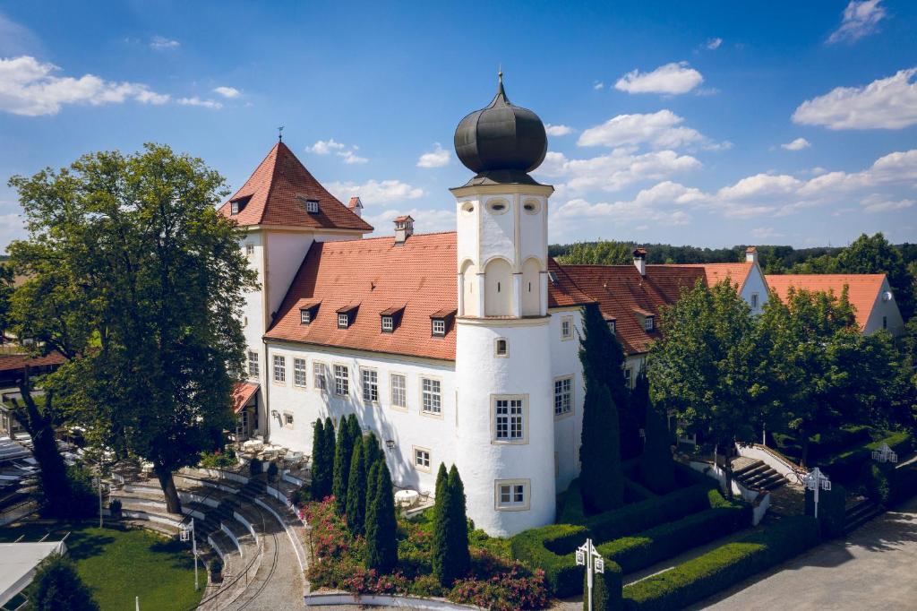 een groot wit gebouw met een rood dak bij Schlosshotel Neufahrn in Neufahrn in Niederbayern