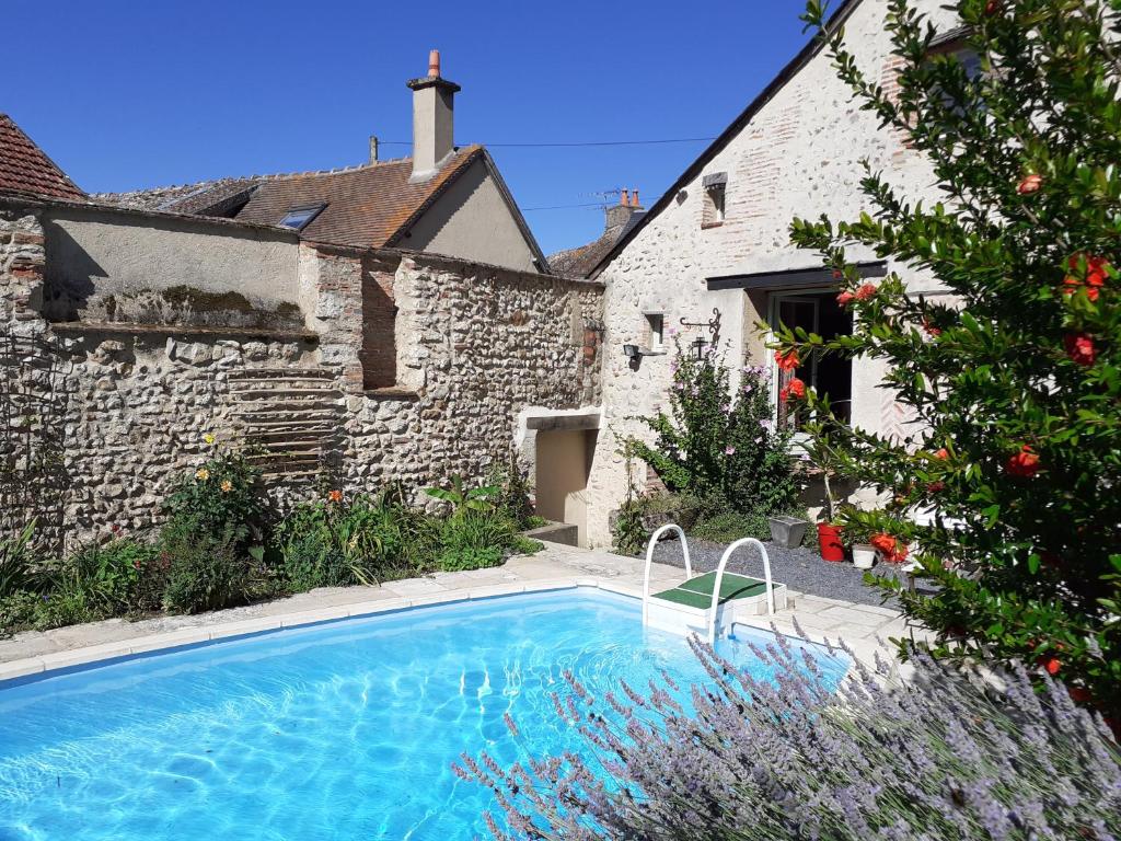 Ousson-sur-Loire的住宿－La Chaumière，一座游泳池,位于一座建筑旁的院子内
