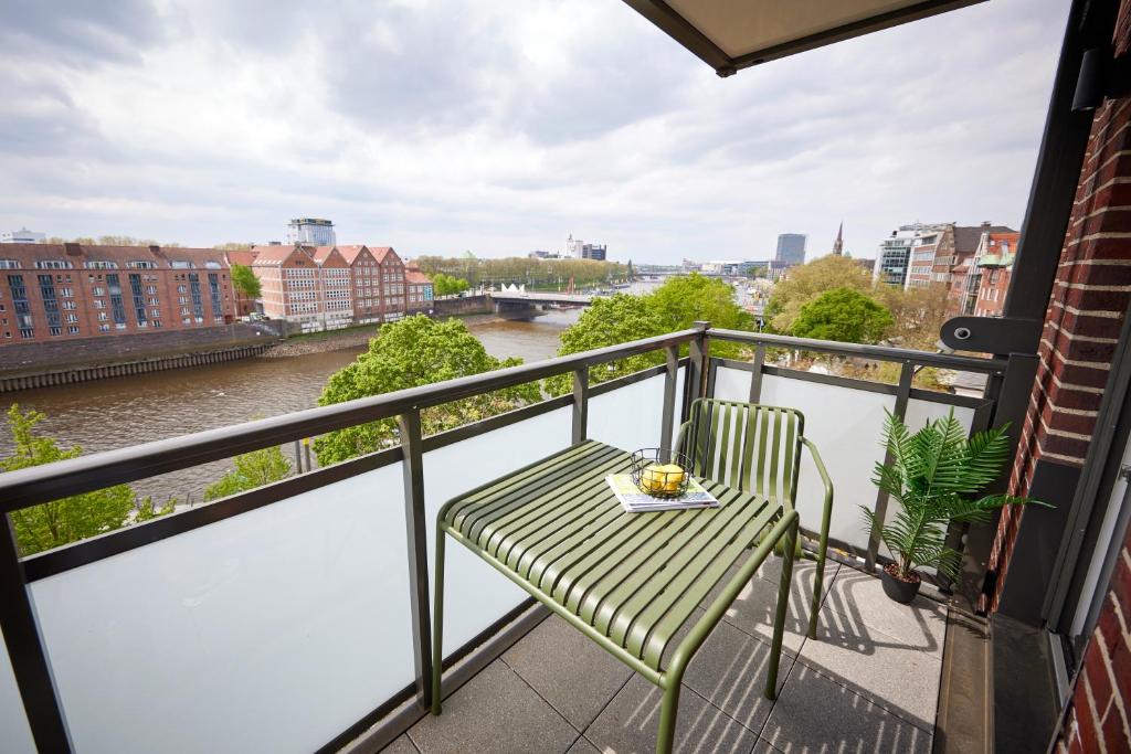 een balkon met een groene stoel en een rivier bij Schlachte 22 Living in Bremen