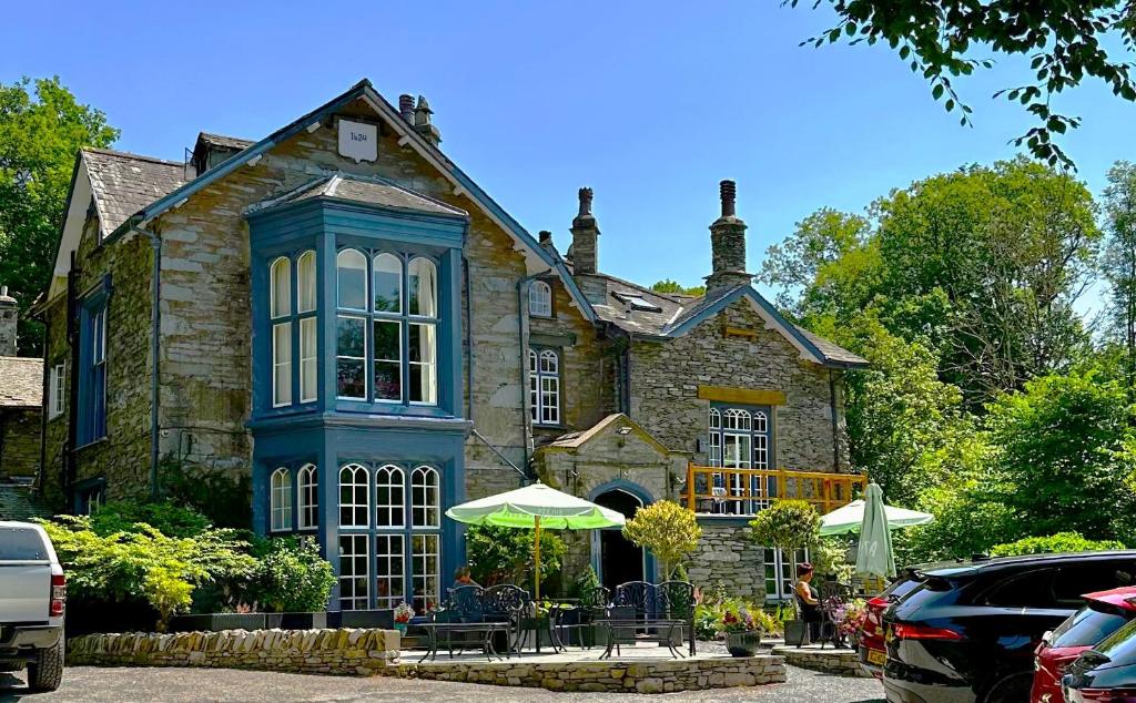 uma grande casa de pedra com uma mesa e um guarda-chuva em Badger Bar em Ambleside