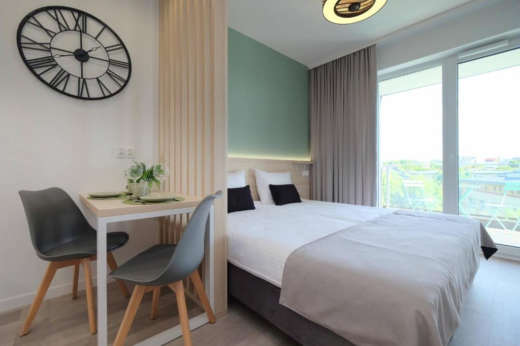 a bedroom with a bed and a desk and a clock at Apartamenty Centrum in Białystok