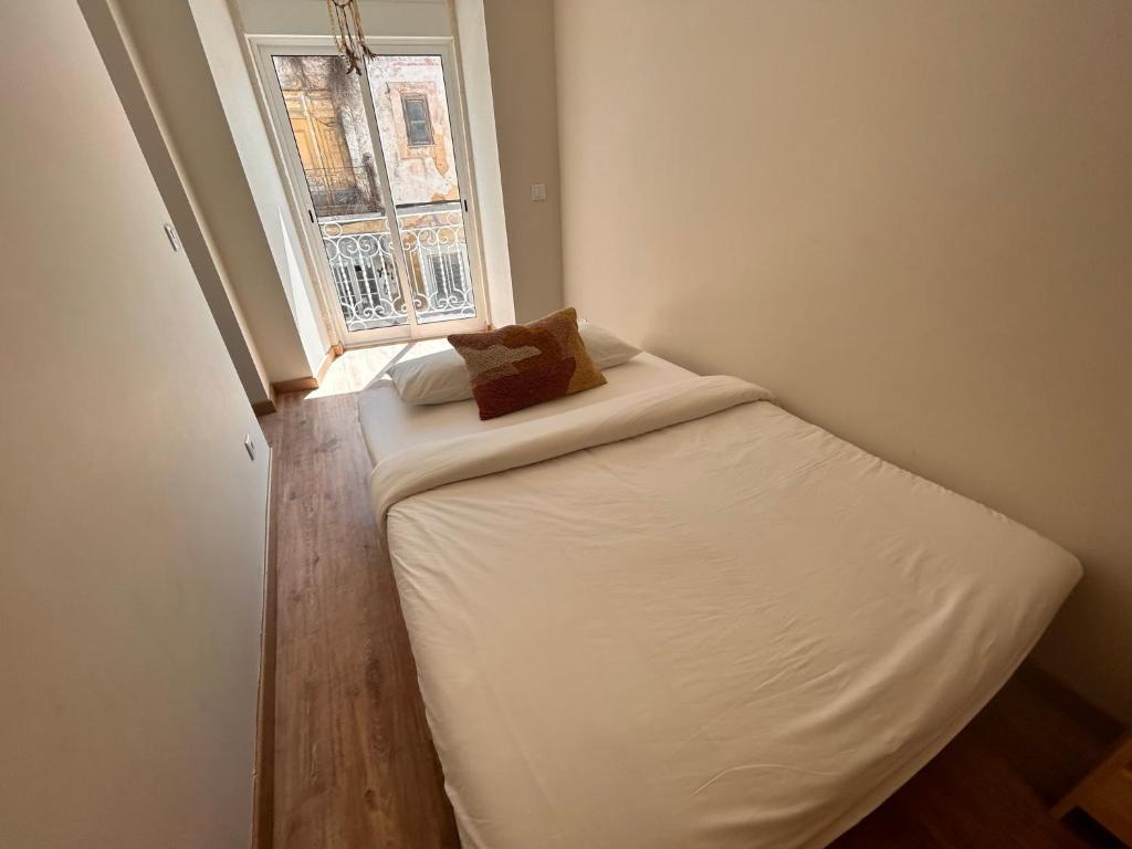 een klein bed in een kamer met een raam bij Moradia Fonte Nova Setúbal in Setúbal