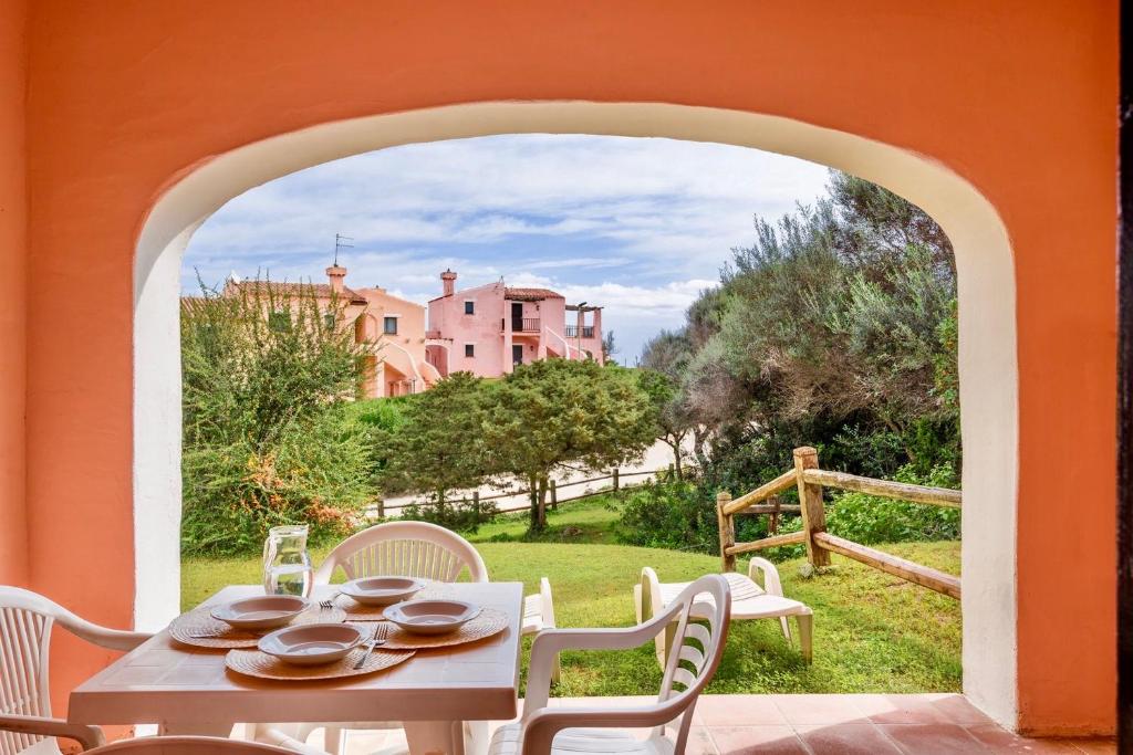 a table and chairs on a patio with a view of a house at Villas with air conditioning and private outdoor area just a few minutes from La Pelosa in Cuile Pazzoni