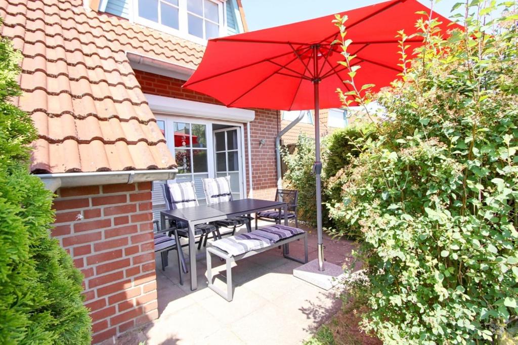 um pátio com uma mesa e um guarda-chuva vermelho em Zweite Heimat inkl WLAN em Grömitz