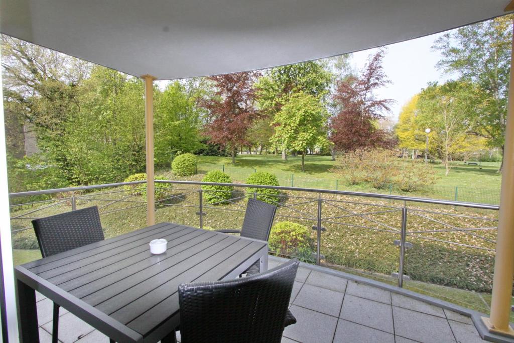 d'une table et de chaises sur un balcon avec vue sur un parc. dans l'établissement Residenz am Kurpark App 10 inkl WLAN, à Grömitz