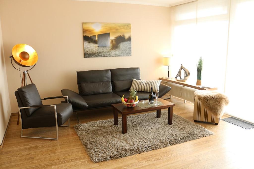 uma sala de estar com um sofá de couro preto e uma mesa em Am Brandungsbad App 1 1 inkl WLAN em Grömitz