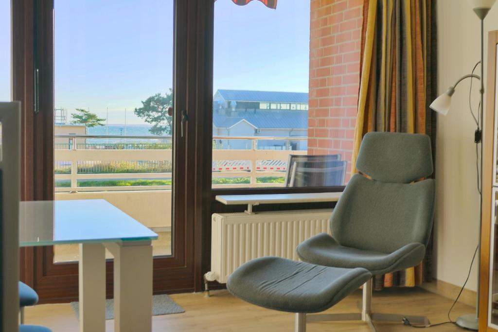 une chambre avec une chaise, une table et une fenêtre dans l'établissement Haus Belvedere App 34 WLAN inkl, à Grömitz