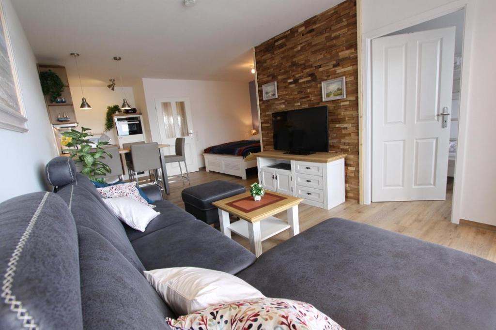 a living room with a gray couch and a television at Kaiserhof App 444 inkl WLAN in Grömitz