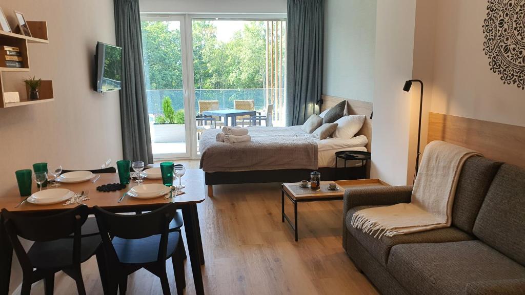 ein Wohnzimmer mit einem Bett, einem Tisch und einem Sofa in der Unterkunft Apartament Laguna Beskidów 57 Góry i Jezioro - Dream Apart in Zarzecze