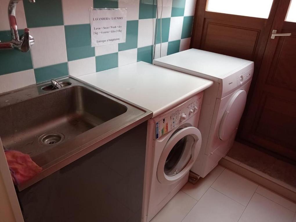 uma cozinha com uma máquina de lavar roupa e um lavatório em Albergue de Peregrinos Villa de Luarca em Luarca