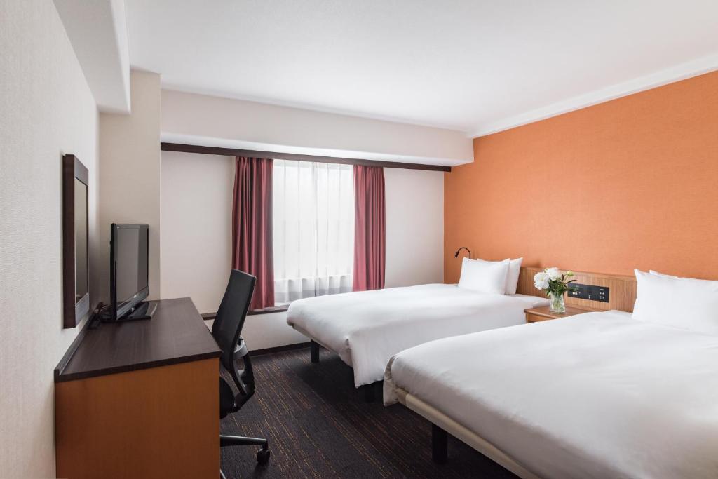 um quarto de hotel com duas camas e uma televisão de ecrã plano em the b nagoya em Nagoia