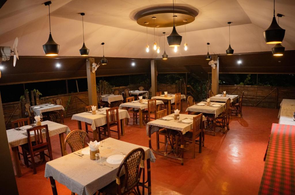 a restaurant with white tables and chairs and lights at Edens Munnar in Munnar
