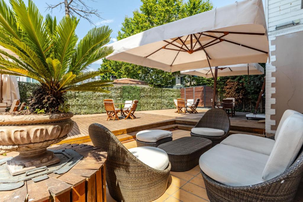 伊斯坦堡的住宿－Sakine Hanim Mansion，庭院配有椅子和一张带遮阳伞的桌子。
