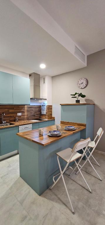 a kitchen with a blue island with two chairs at Apto Lux Sevilla in Seville