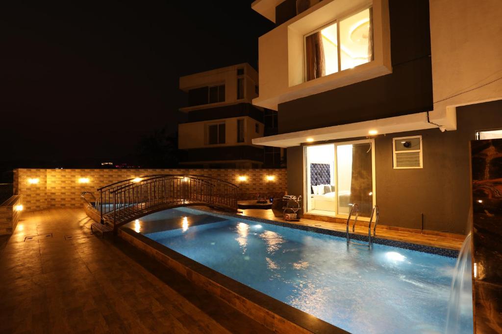 a swimming pool in front of a building at night at Casa Lola in Lonavala