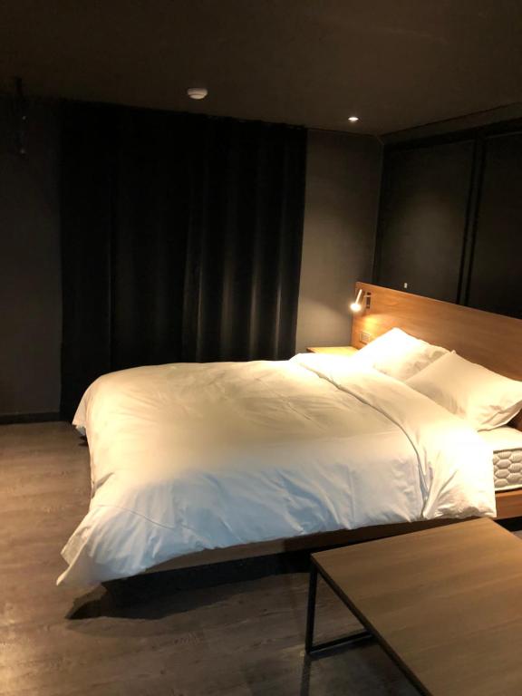 a large white bed in a room with a table at Soho Hotel in Busan