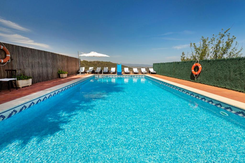 a large swimming pool with blue water at 21 Sleeps Private Pool Villa & BBQ Near Barcelona in Rocafort