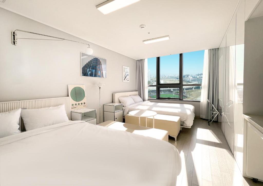 a white hotel room with two beds and a window at UH FLAT THE SONGDO in Incheon