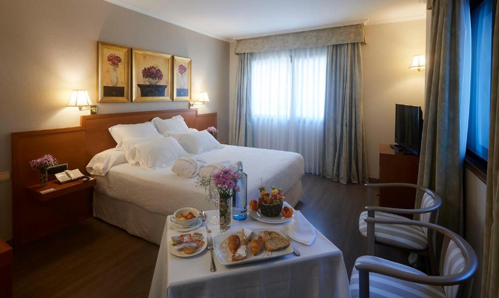 una habitación de hotel con una cama y una mesa con comida. en Galicia Palace en Pontevedra
