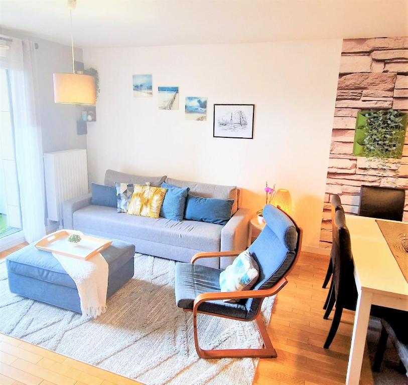 uma sala de estar com um sofá azul e cadeiras em Modern and confortable apartment close to Paris em Bois-Colombes