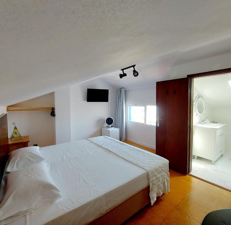 a bedroom with a large white bed and a window at Soleil Bleu in Vila Nova de Milfontes