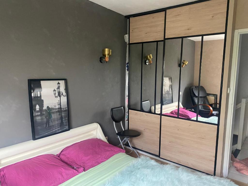 - une chambre dotée d'un lit avec des draps roses et un miroir dans l'établissement Agréables chambres dans maison suspendue, à Saint-Étienne