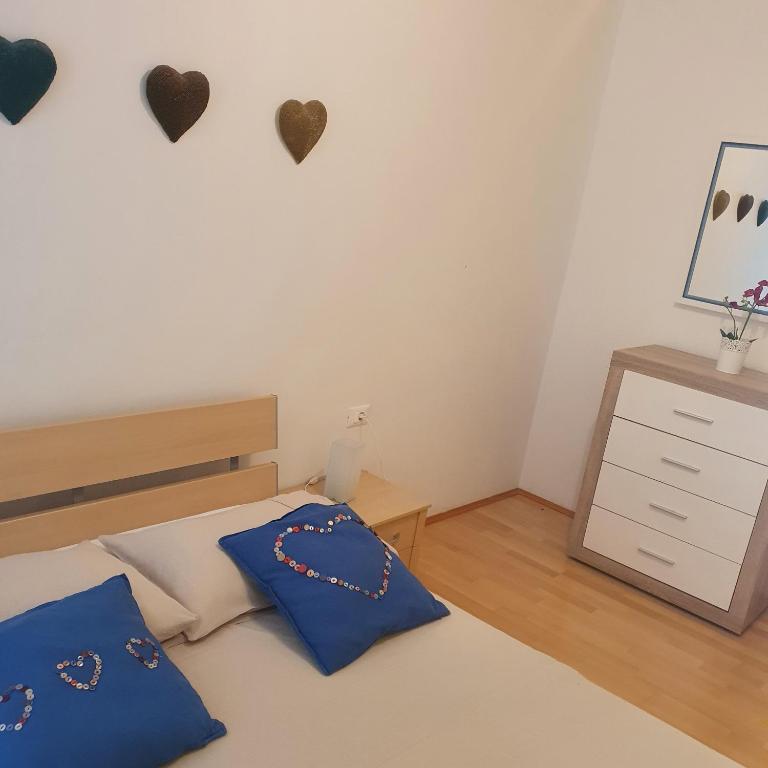 a bedroom with a bed with blue pillows and hearts on the wall at Dee&#39;s House and Pool in Labin