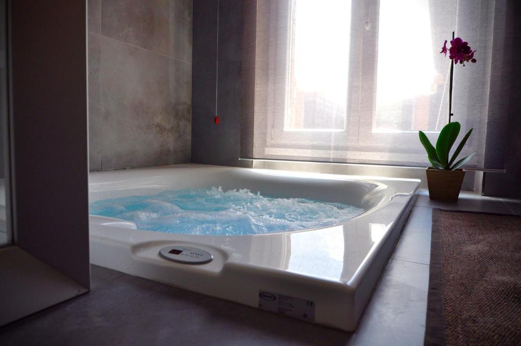 El baño incluye bañera con agua azul. en Place 24 Suites & Wellness, en Roma