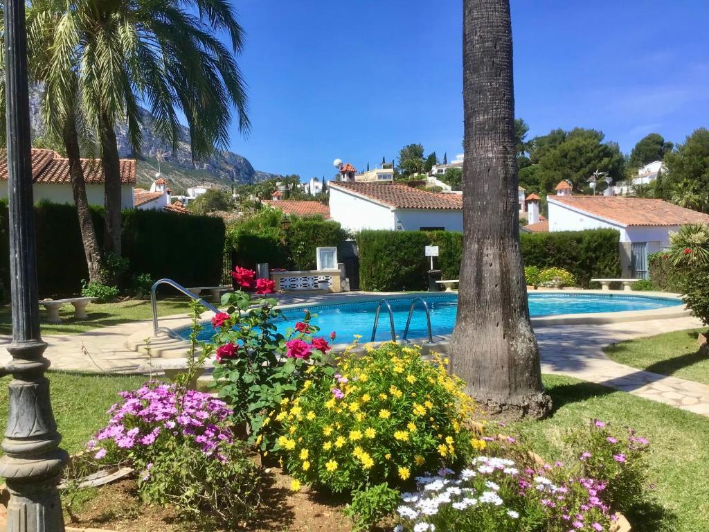 einen Garten mit Blumen neben einem Pool in der Unterkunft Casa de 2 dormitorios con piscina, 2 terrazas privadas, WIFI, BBQ in Denia